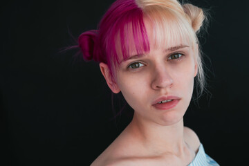 Close up portrait of Young adult woman with pink and white hair looking at camera.