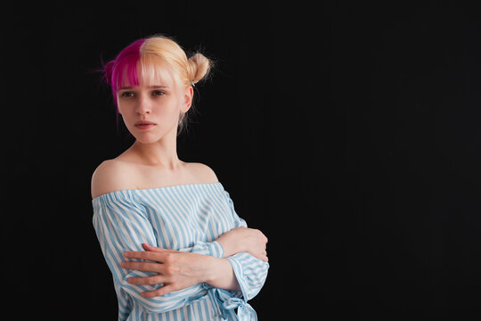 Young Adult Woman With Pink And White Hair Self Hugging On Black Background