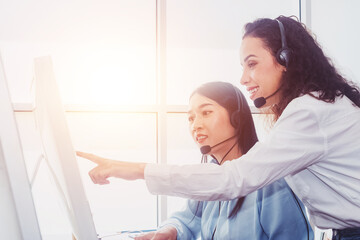 Obraz premium Women team call center workers in headphones are working at modern office.