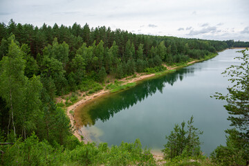 Summer moment at the Dubkalni quarry in Ogre with surrounding forest and green, transparent water on a cloudy day in July in Latvia