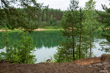 Summer moment at the Dubkalni quarry in Ogre with surrounding forest and green, transparent water on a cloudy day in July in Latvia