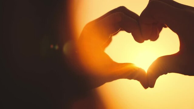 heart sign silhouette sunset. show with hands shape heart glare sun. freedom travel young girl. close-up heart. cheerful romantic evening. heart against sky. concept love future world. hand heart.