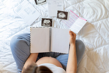 Pregnant woman writing list. Young pregnancy mother holding notepad. Pregnant lady writing check...