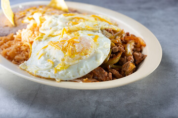 A view of a plate of steak ranchero with eggs.
