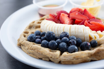 A view of a gluten-free waffles topped with assorted fruit.
