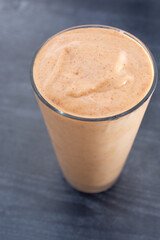 A view of a yellow orange cold smoothie beverage.