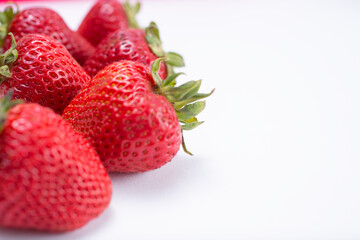 A view of strawberries on a white background, on the left side of the frame.