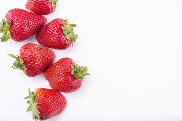 A top down view of strawberries on a white background, on the left side of the frame.