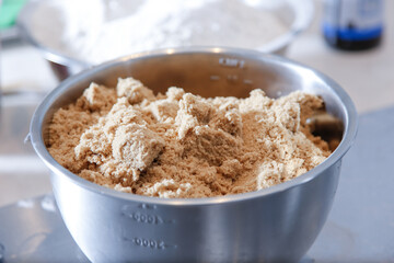 A view of a large stainless steel bowl of brown sugar.