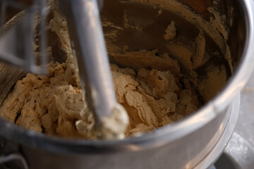 A view of a commercial grade dough mixer, seen in a bakery setting.