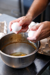 A view of an employee's hands breaking eggs into a bowl.
