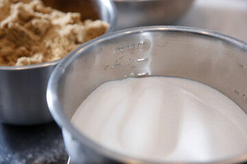 A view of a big stainless steel bowl of white granulated sugar.