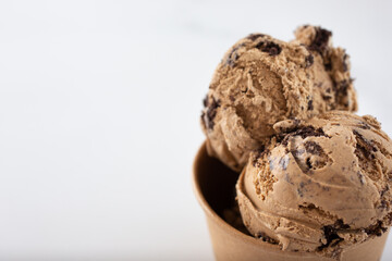A view of a cup of chocolate ice cream scoops, on the right side of the frame.