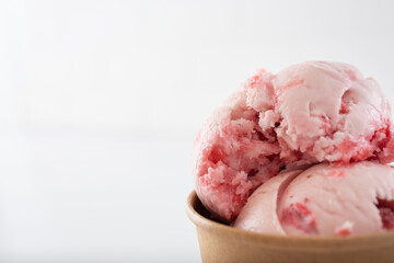 A view of a cup of strawberry ice cream scoops, on the right side of the frame.