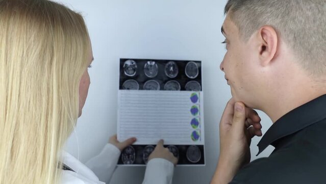 Epileptologist examines patient MRI and electroencephalogram. Concept treating epilepsy and helping people who suffer from this disease. Neurologist at work. Pathology of the brain. Seizure activity