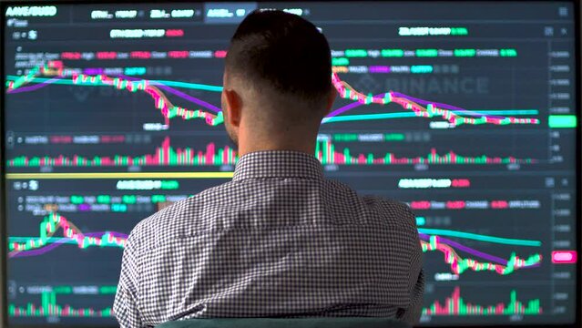 Professional trader analyzing stock market data on computer scren and taking notes