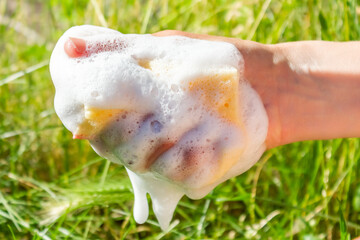 The human hand squeezes out a sponge. Yellow sponge with foam. - obrazy, fototapety, plakaty
