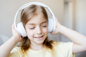 Cute child using headphones at home. Little kid girl having fun at home. Childhood concept.