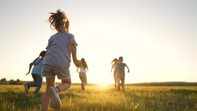 Happy holiday in nature. Family and friend run together on green grass in summer.Active children walk in the park at sunset.Child have fun play and run in spring in field.Family picnic on green grass.