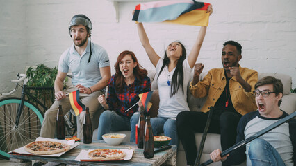 Multi ethnic group of friends sports fans with German national flags watching hockey championship...