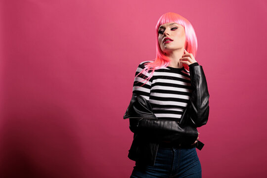 Sensual punk adult wearing rocker leather jacket in studio, expressing carefree funky fashion style. Attractive beautiful lady with trendy clothes and stylish pink hair, cute makeup.