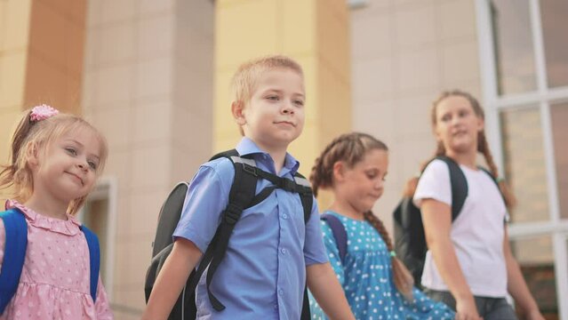 back to school. a group of schoolchildren with backpacks walk next to the school. education lifestyle kids concept. schoolboy and schoolgirl going to school. a group of children walking