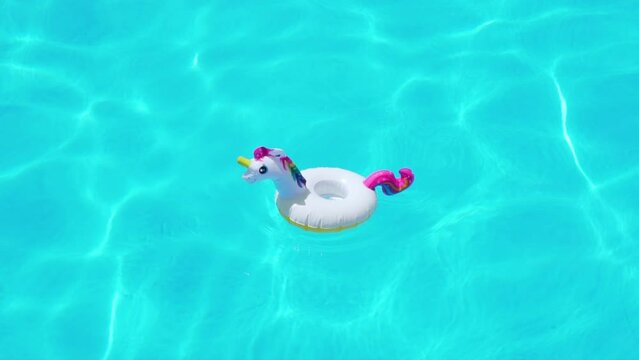 Inflatable Unicorn Toy in Clear Blue Green Water of Ocean Sea Pool in Sunlight on Sunny Day, Nobody. Unicorn is Swaying on Waves in Beautiful Pure Turquoise Water. 