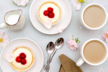 Fototapeta na wymiar Delicious red raspberry strawberry whipped creamy tartlets,cakes.gourmet confection dessert on plate with latte coffee,milk.sweet tasty pastry baked pie cheesecake with ripe berries on gray table