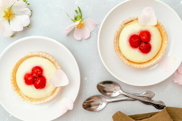 Delicious red raspberry strawberry whipped creamy tartlets,cakes.gourmet confection dessert on plate with latte coffee,milk.sweet tasty pastry baked pie cheesecake with ripe berries on gray table