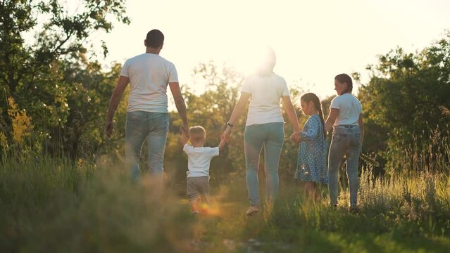 Happy family. Parents and children walk on the green grass. People at a picnic in the park. Family having fun together in field. Father and mom with children in a natural park. Happy people concept