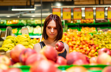 Woman in a supermarket at the shelf for fruits shopping apple