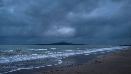 Dramatic stormy sky over Rangitoto Island, Milford beach, Auckland. Concept of hard time ahead.