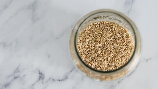 pantry jar with brown rice shot from top down perspective as close-up, simple staple ingredients