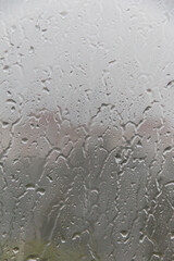 Raindrops drip down on the window glass. Soft selective focus.