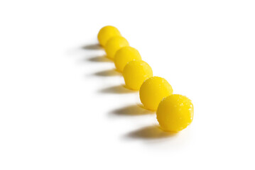 a line of six yellow candies on a white background. selective focus