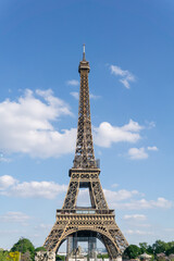 Fototapeta na wymiar Photograph of the eiffel tower on a sunny day in portrait format with blue sky and white clouds.