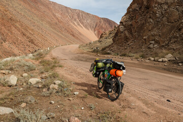 Tourist bike on a mountain road. traveler's bike with bags stand on the Mountain road. Kyrgyzstan