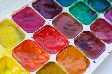 Palette with watercolor multi-colored paints, side view, selective focus, close-up paints