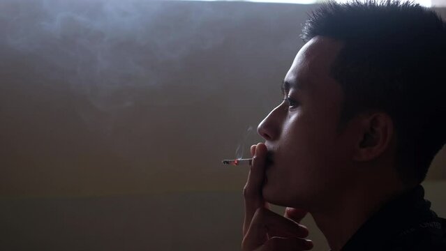 Asian man smoking cigarette in smoke area and spit spray