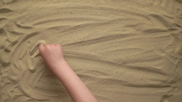 man writes the word kudos on the sand