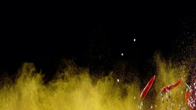 Mixture of ground spices, assorted peppers, salt and small red chili peppers slowly rise and fall against a black background. 300fps