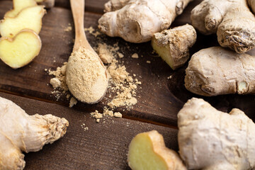 Freshly chopped ginger root and ground ginger powder in wooden spoon on wooden rustic table. Healthy food seasoning concept.