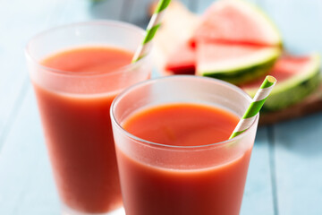 Fresh watermelon juice in glass on blue wooden table. Close up