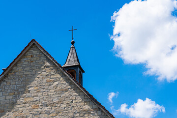 Part of the church roof with a cross against a blue sky .