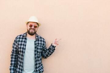 Handsome caucasian man wearing summer hat and plaid shirt smiling happy near wall with copy space - travel vacations and summer holiday concept