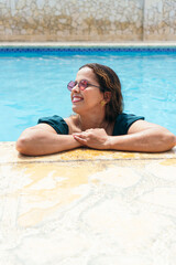 woman with sunglasses relaxing by the summer pool