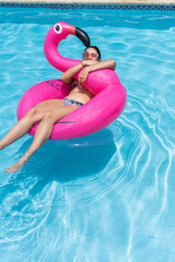 woman relaxing, floating in inflatable ring in sunny summer swimming pool