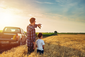 father and son outdoor on wheat field. farmers life concept. father showing their land to his son