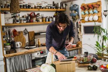 man looking for recipes on digital tablet. preparing food in his home kitchen