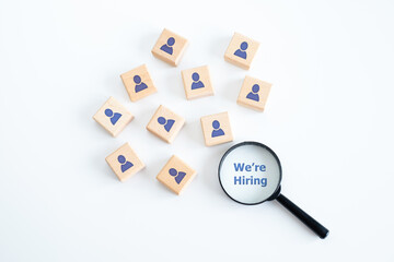 Human resources management and recruitment business hiring concept, professional staff research, head hunter, magnifying glass with We're Hiring text looking for employees on wood cube.